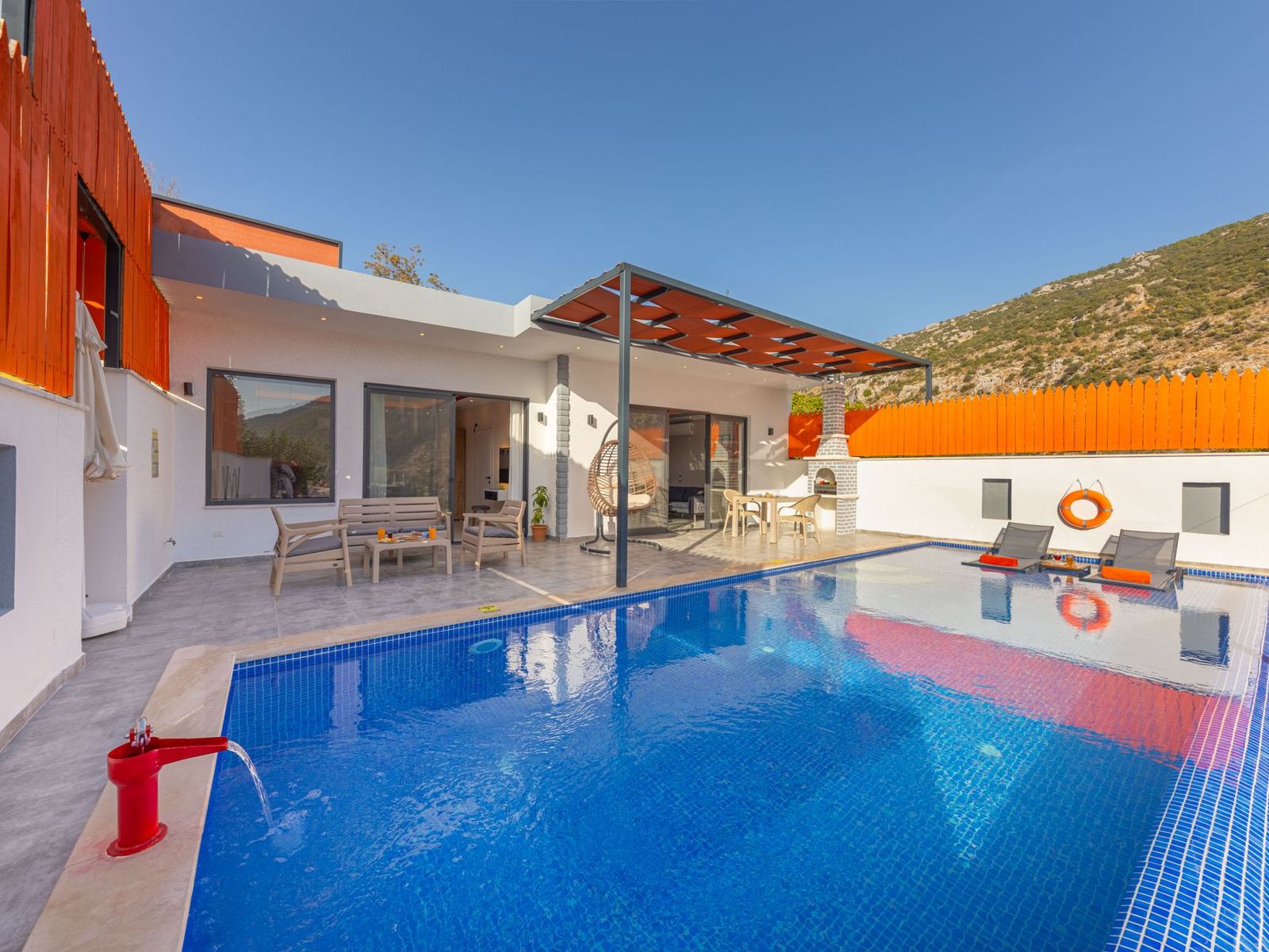 Backyard inground swimming pool beside a modern home and patio